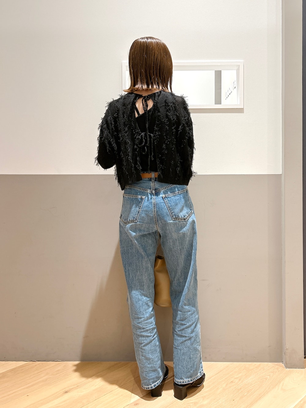 ブラック系のニット/セーター、ブルー系のデニムパンツ、ブラック系のサンダルを着用したレディースの春コーディネートの2枚目の写真