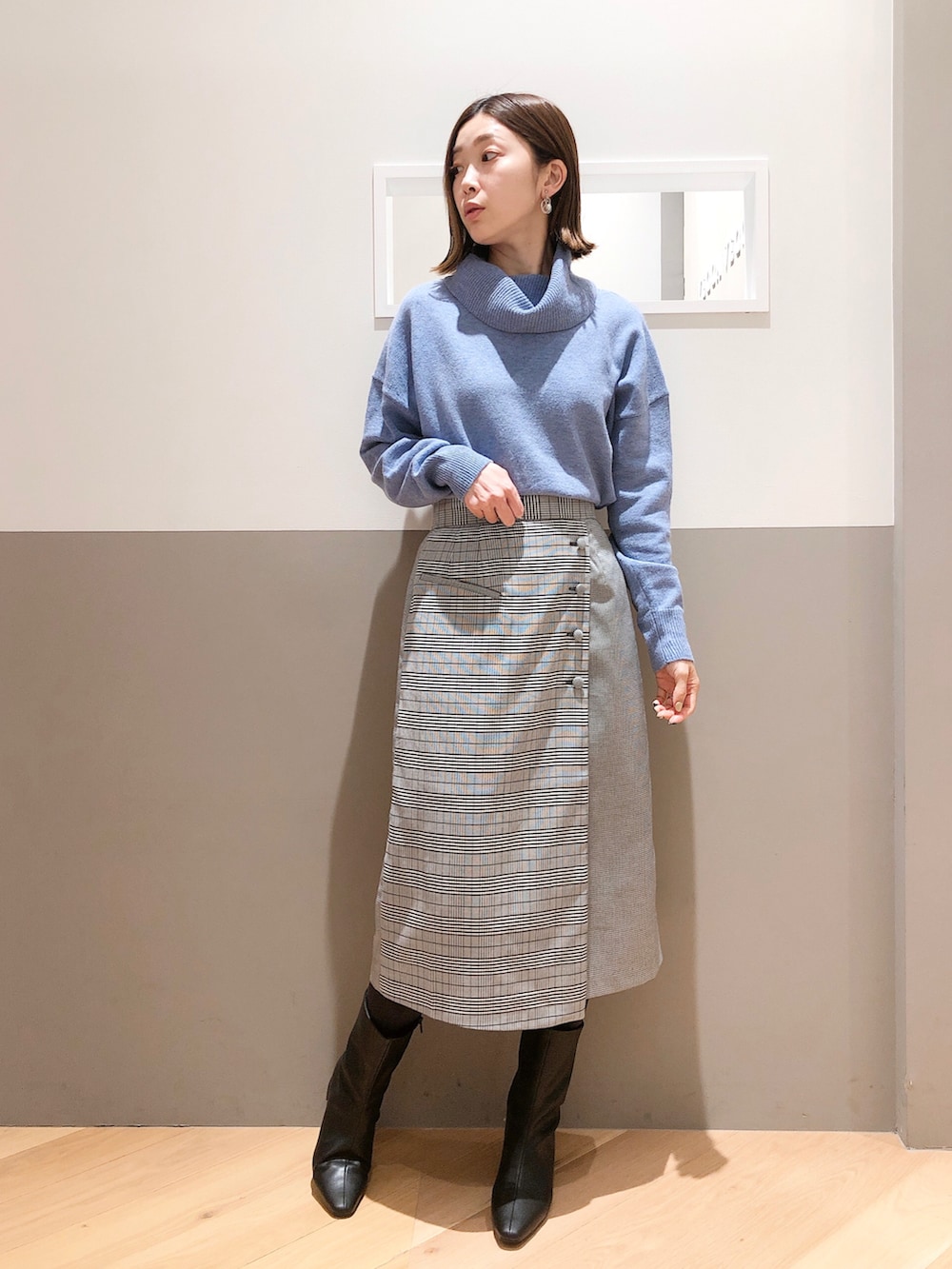 ベージュ系のノーカラーコート、ブルー系のニット/セーター、ブラック系のスカートを着用したレディースの冬コーディネートの2枚目の写真