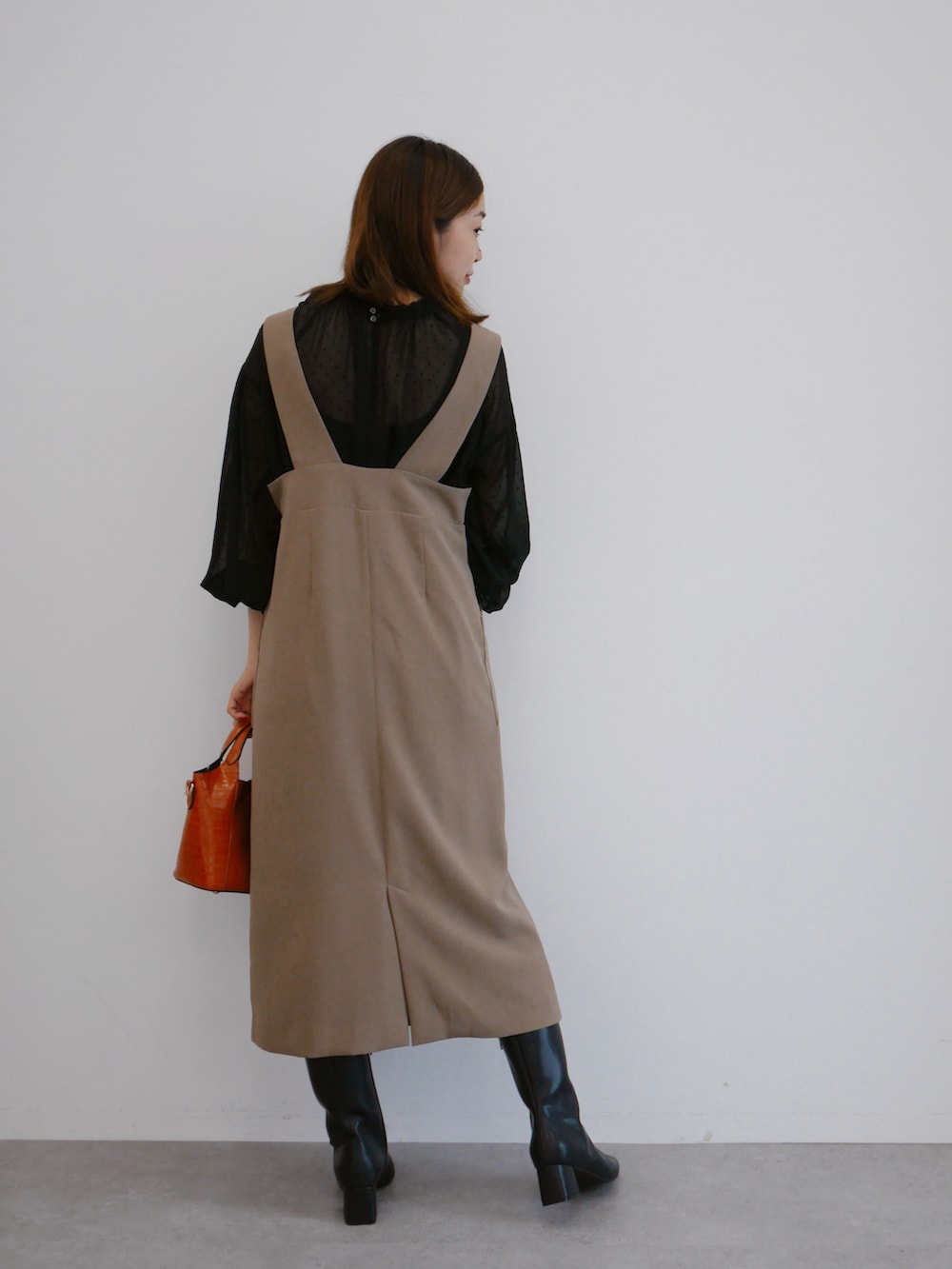 ベージュ系のジャンパースカート、ブラック系のシャツ/ブラウス、オレンジ系のハンドバッグを着用したレディースの秋コーディネートの2枚目の写真