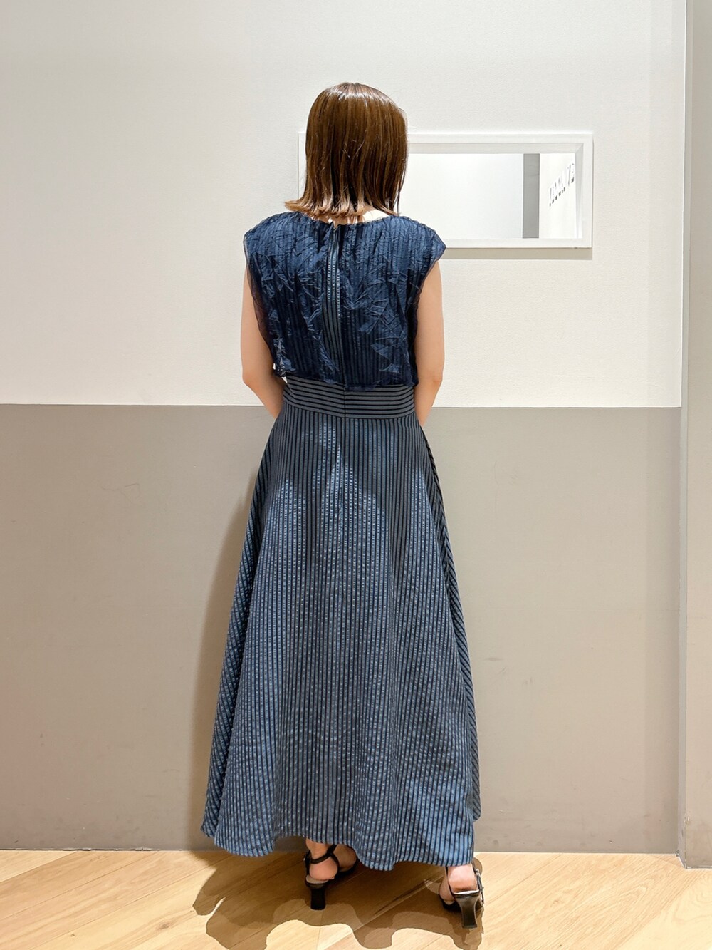 ブルー系のワンピース、ブラック系のサンダル、ゴールド系のイヤリングを着用したレディースの夏コーディネートの2枚目の写真