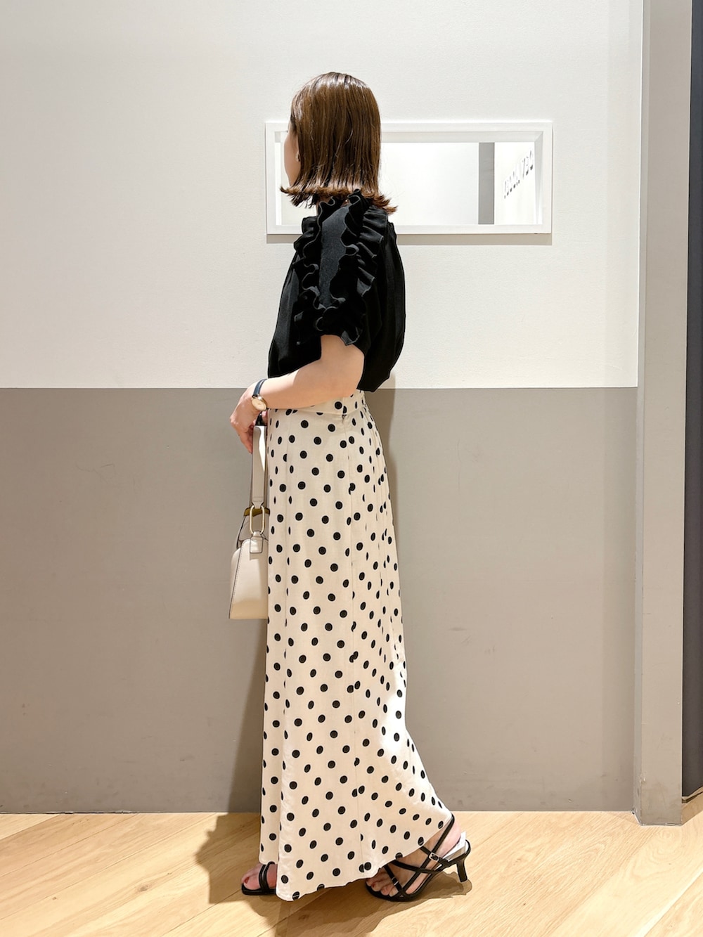 ブラック系のシャツ/ブラウス、ベージュ系のスカート、ブラック系のサンダルを着用したレディースの夏コーディネートの2枚目の写真