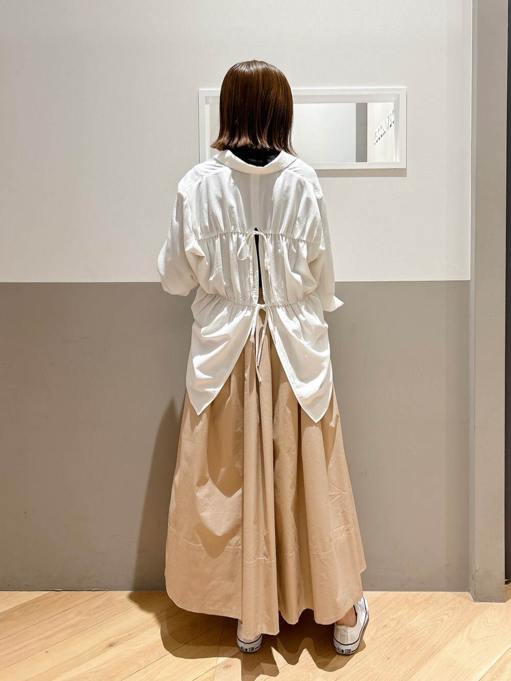 ホワイト系のシャツ/ブラウス、ブラック系のTシャツ/カットソー、ベージュ系のスカートを着用したレディースの春コーディネートの2枚目の写真