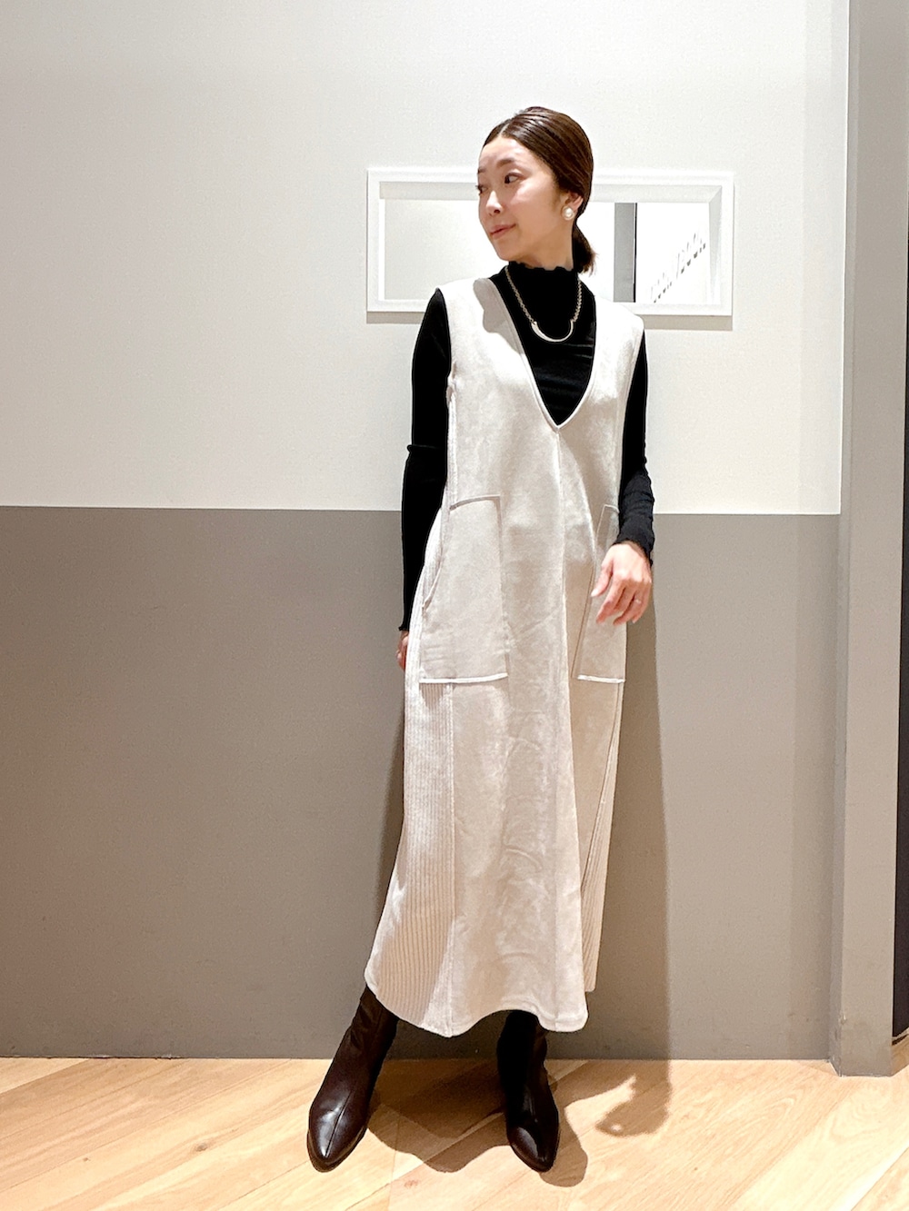 ブラック系のカーディガン/ボレロ、ベージュ系のジャンパースカート、ブラック系のTシャツ/カットソーを着用したレディースの冬コーディネートの2枚目の写真