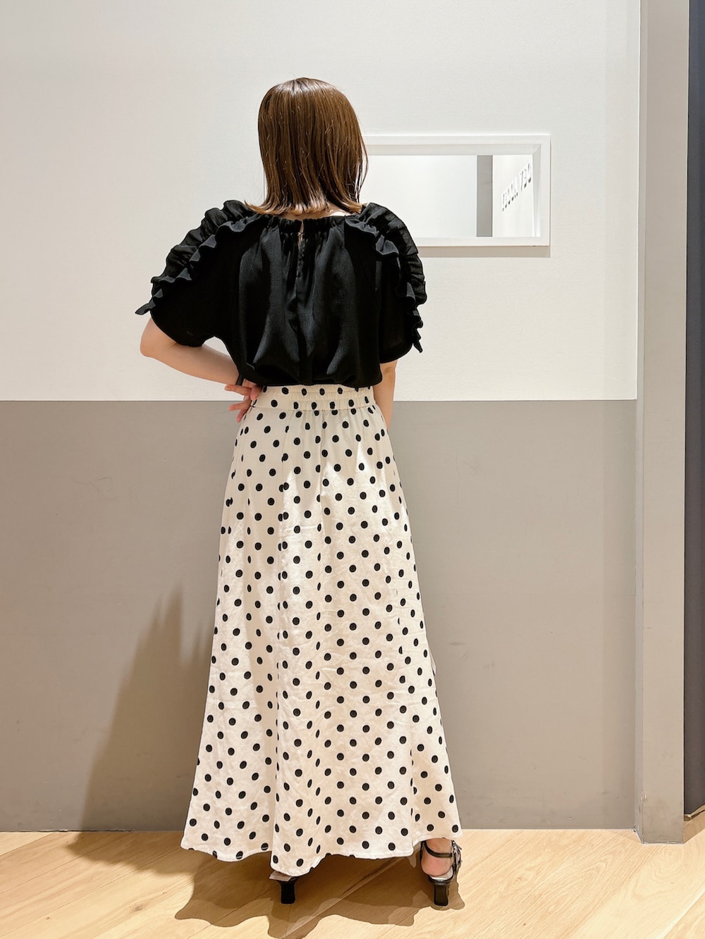 ブラック系のシャツ/ブラウス、ベージュ系のスカート、ブラック系のサンダルを着用したレディースの夏コーディネートの3枚目の写真