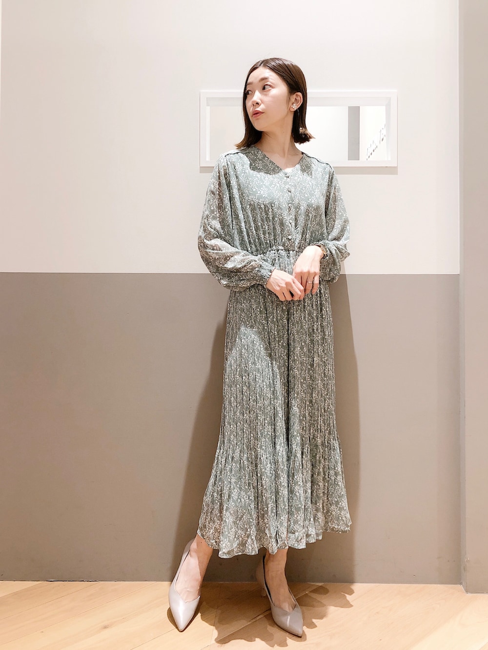 ホワイト系のトレンチコート、グリーン系のワンピース、グリーン系のトートバッグを着用したレディースの春コーディネートの2枚目の写真