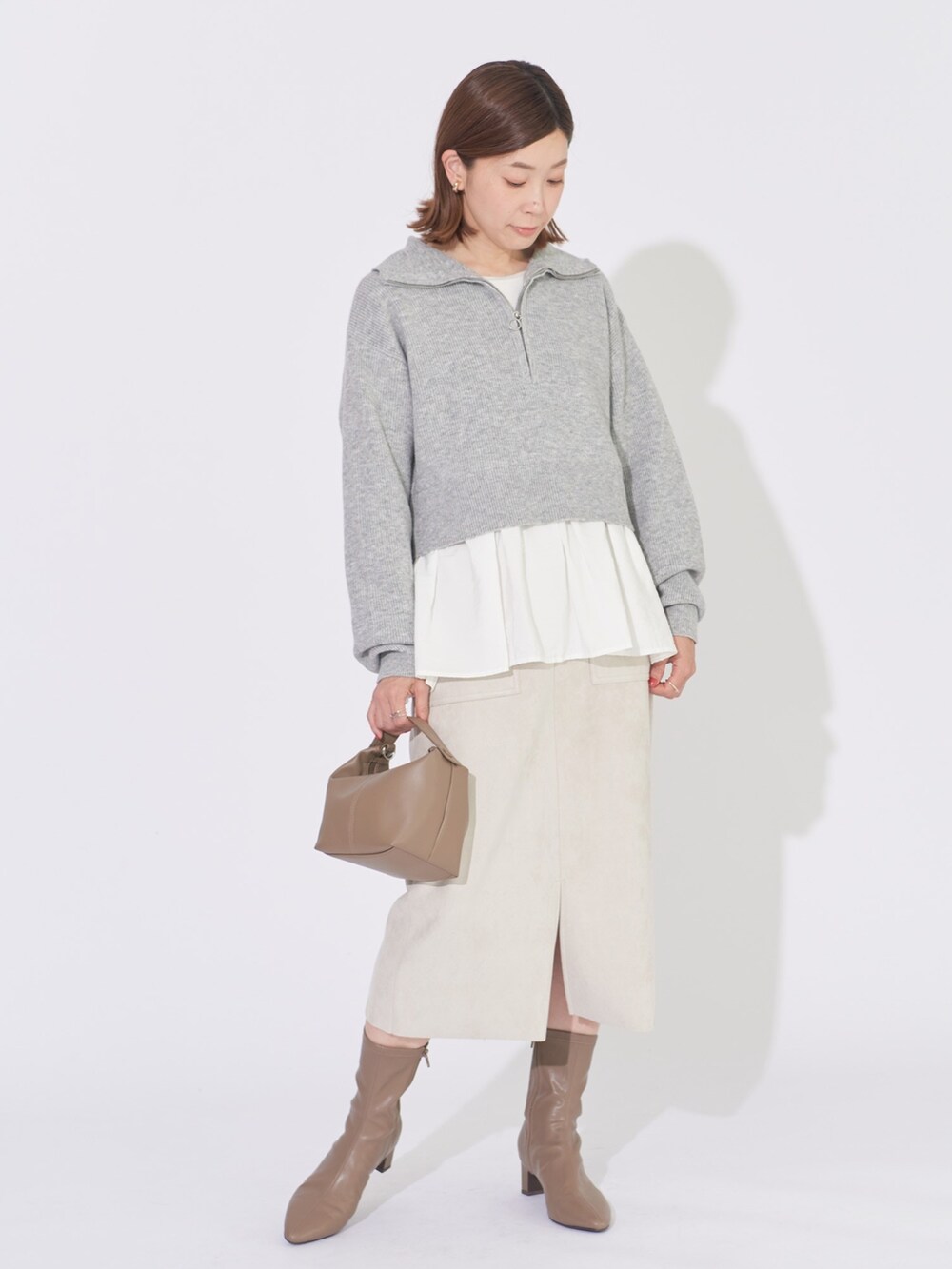 グレー系のニット/セーター、ベージュ系のスカートを着用したレディースの冬コーディネートの2枚目の写真