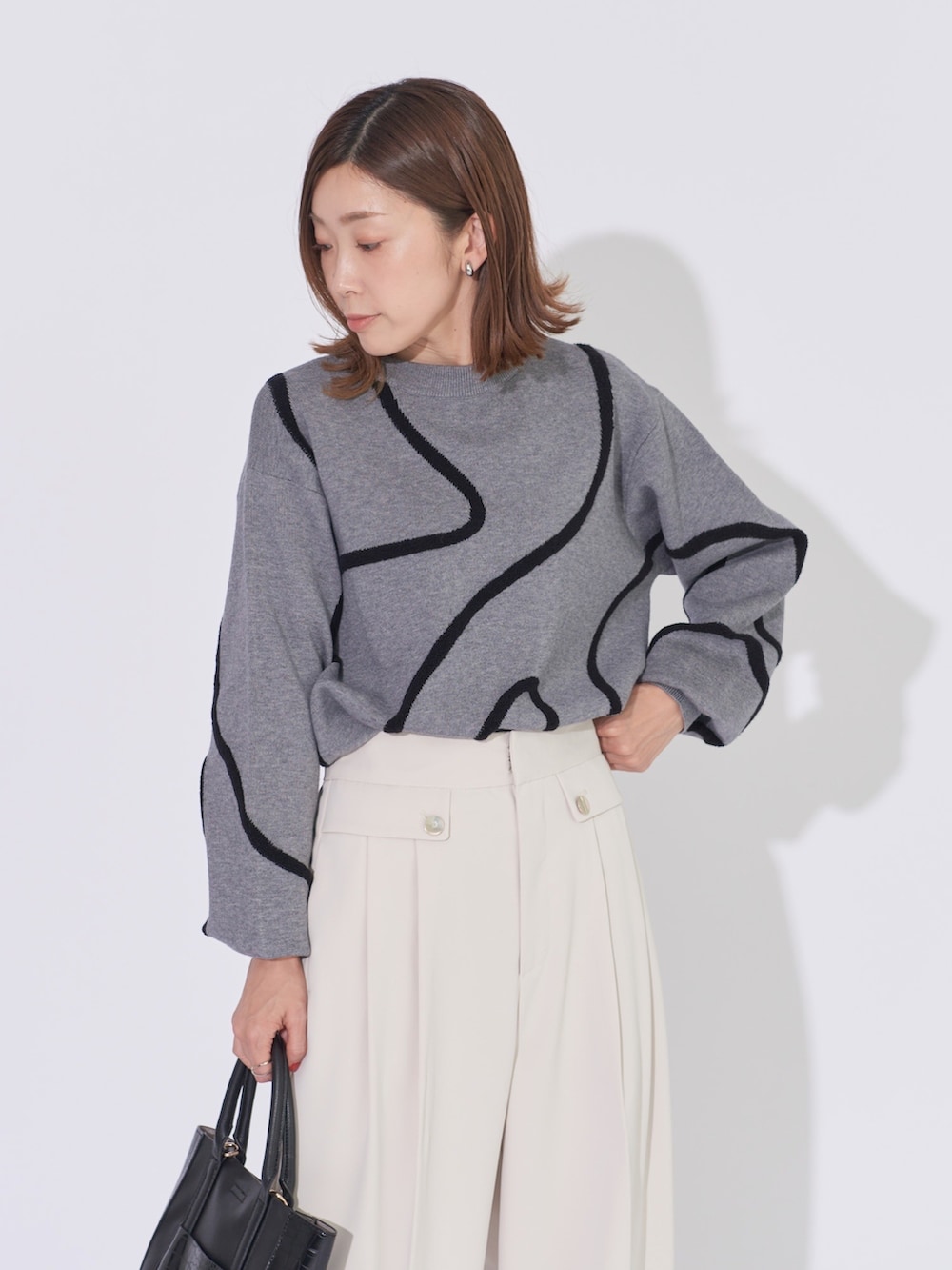 グレー系のニット/セーター、ホワイト系のその他パンツ、ブラック系のトートバッグを着用したレディースの冬コーディネートの3枚目の写真