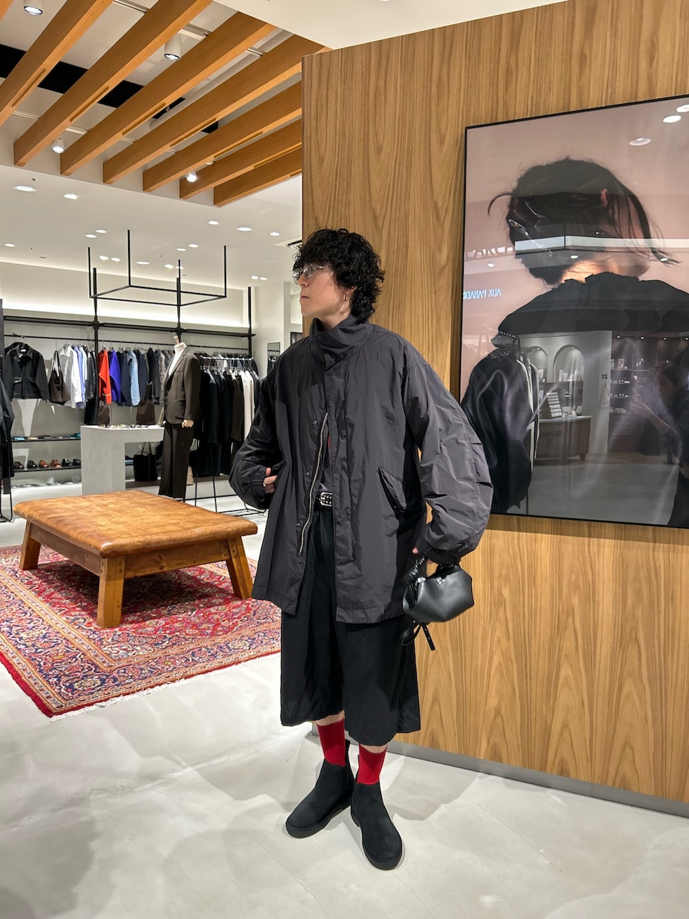 ブラック系のモッズコート、ブラック系のハンドバッグ、ブラック系のその他シューズを着用したメンズの秋コーディネートの5枚目の写真