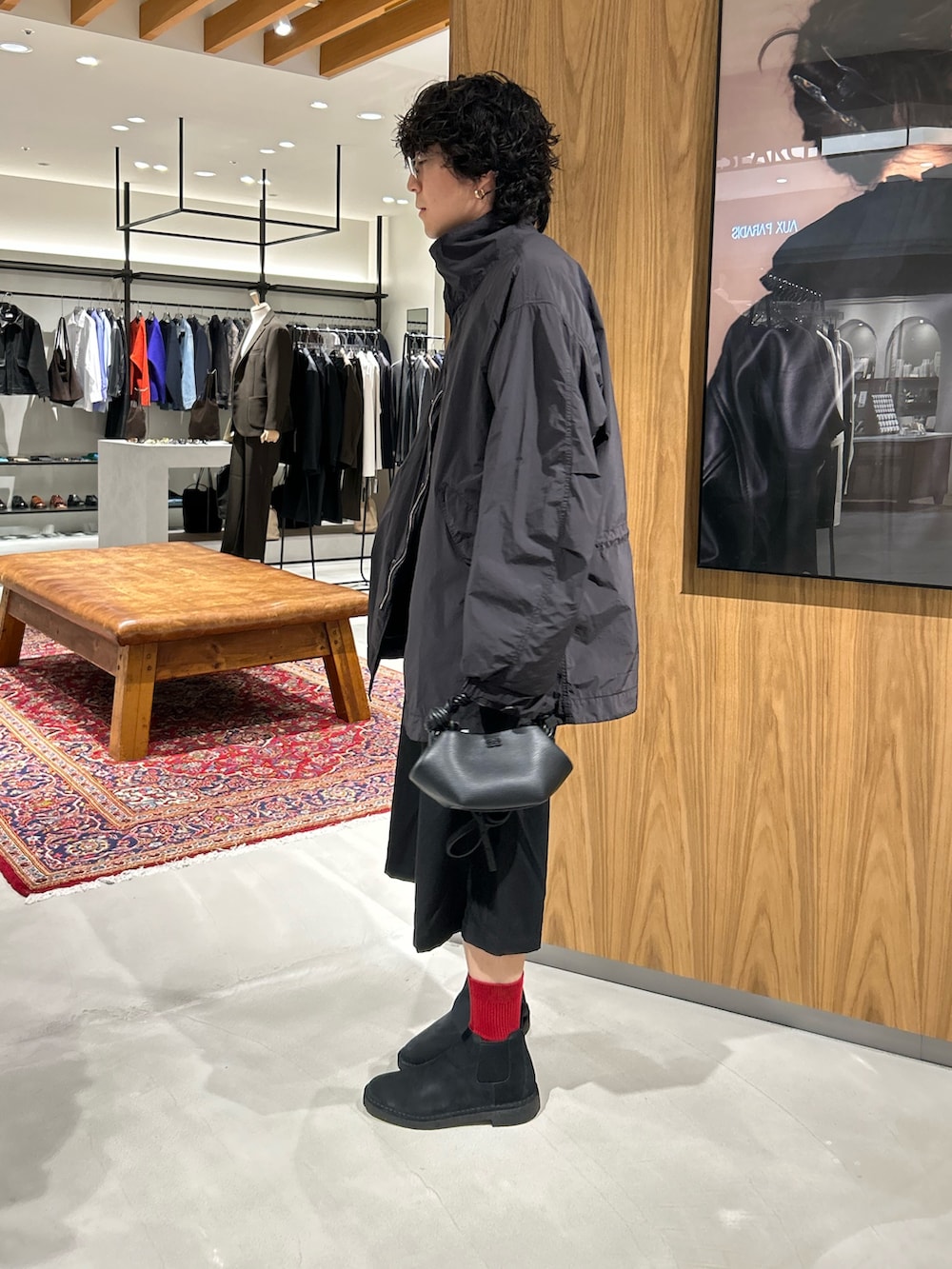 ブラック系のモッズコート、ブラック系のハンドバッグ、ブラック系のその他シューズを着用したメンズの秋コーディネートの3枚目の写真