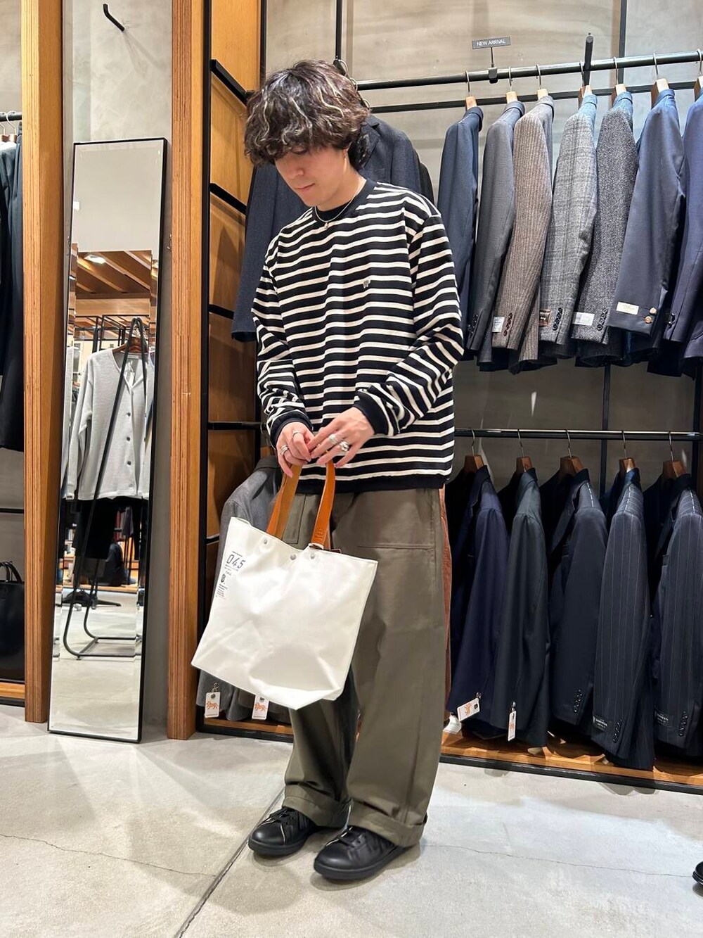 ホワイト系のトートバッグ、ブラック系のTシャツ/カットソー、グリーン系のチノパンツを着用したメンズの秋コーディネートの3枚目の写真