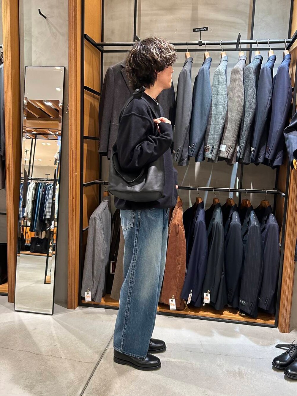 ブラック系のニット/セーター、ブラック系のトートバッグ、ブルー系のデニムパンツを着用したメンズの秋コーディネートの3枚目の写真