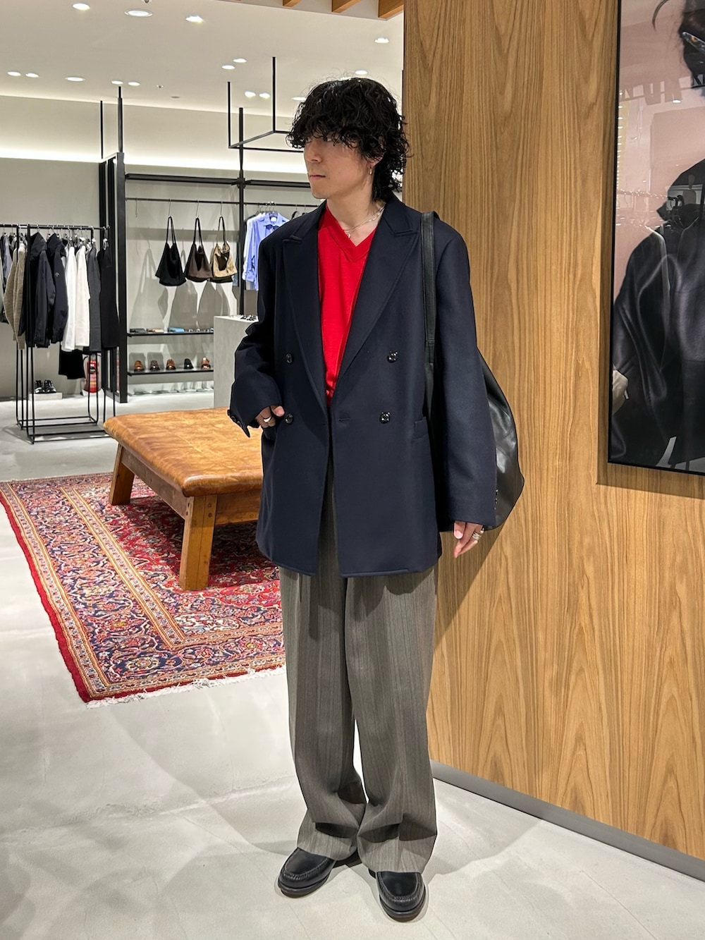 レッド系のニット/セーター、ブラック系のトートバッグ、ブルー系のテーラードジャケットを着用したメンズの秋コーディネートの3枚目の写真