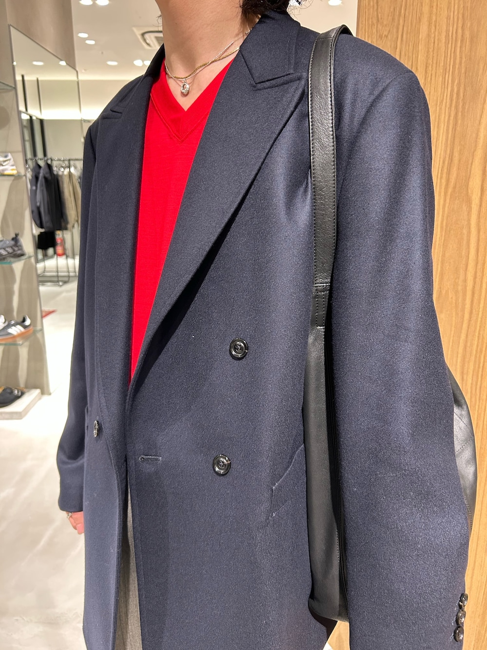 レッド系のニット/セーター、ブラック系のトートバッグ、ブルー系のテーラードジャケットを着用したメンズの秋コーディネートの4枚目の写真