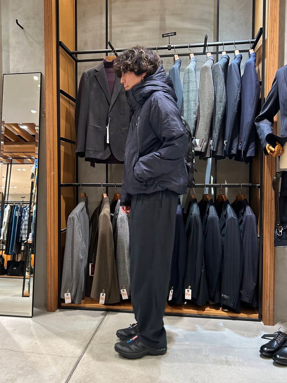 ブラック系のバックパック/リュック、ブラック系のスニーカー、ブルー系のダウンジャケット/コートを着用したメンズの秋コーディネートの2枚目の写真