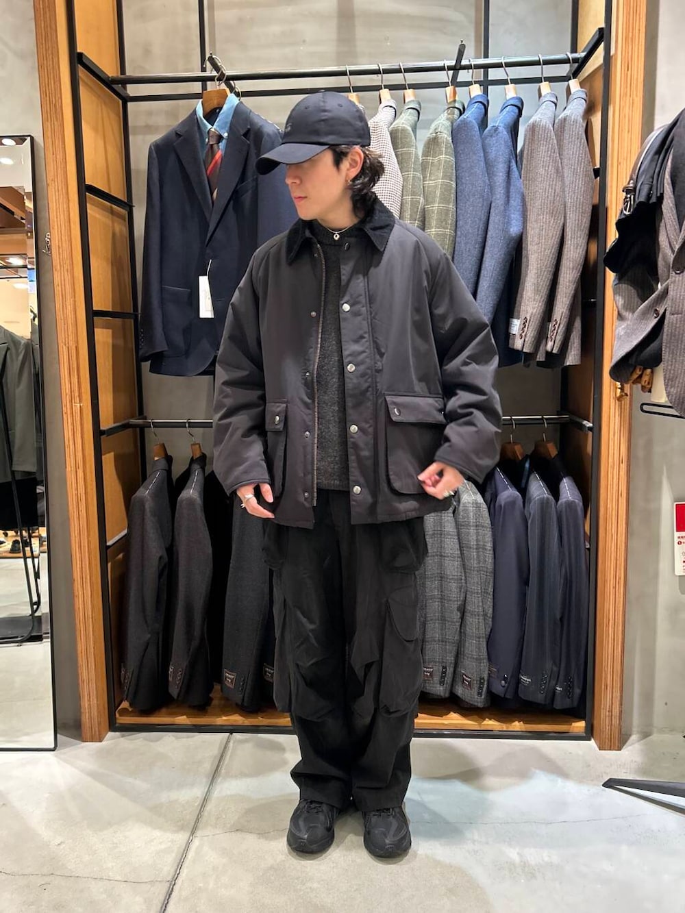 グレー系のニット/セーター、ブラック系のダウンジャケット/コート、ブラック系のキャップを着用したメンズの冬コーディネートの2枚目の写真