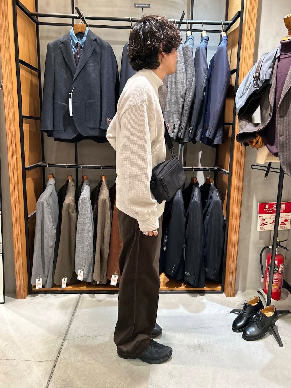 ブラック系のショルダーバッグ、ホワイト系のニット/セーター、ブラウン系のその他パンツを着用したメンズの秋コーディネートの3枚目の写真