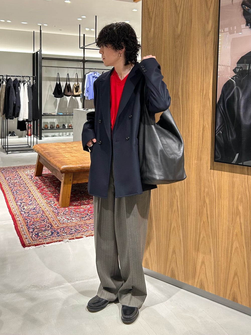 レッド系のニット/セーター、ブラック系のトートバッグ、ブルー系のテーラードジャケットを着用したメンズの秋コーディネートの2枚目の写真