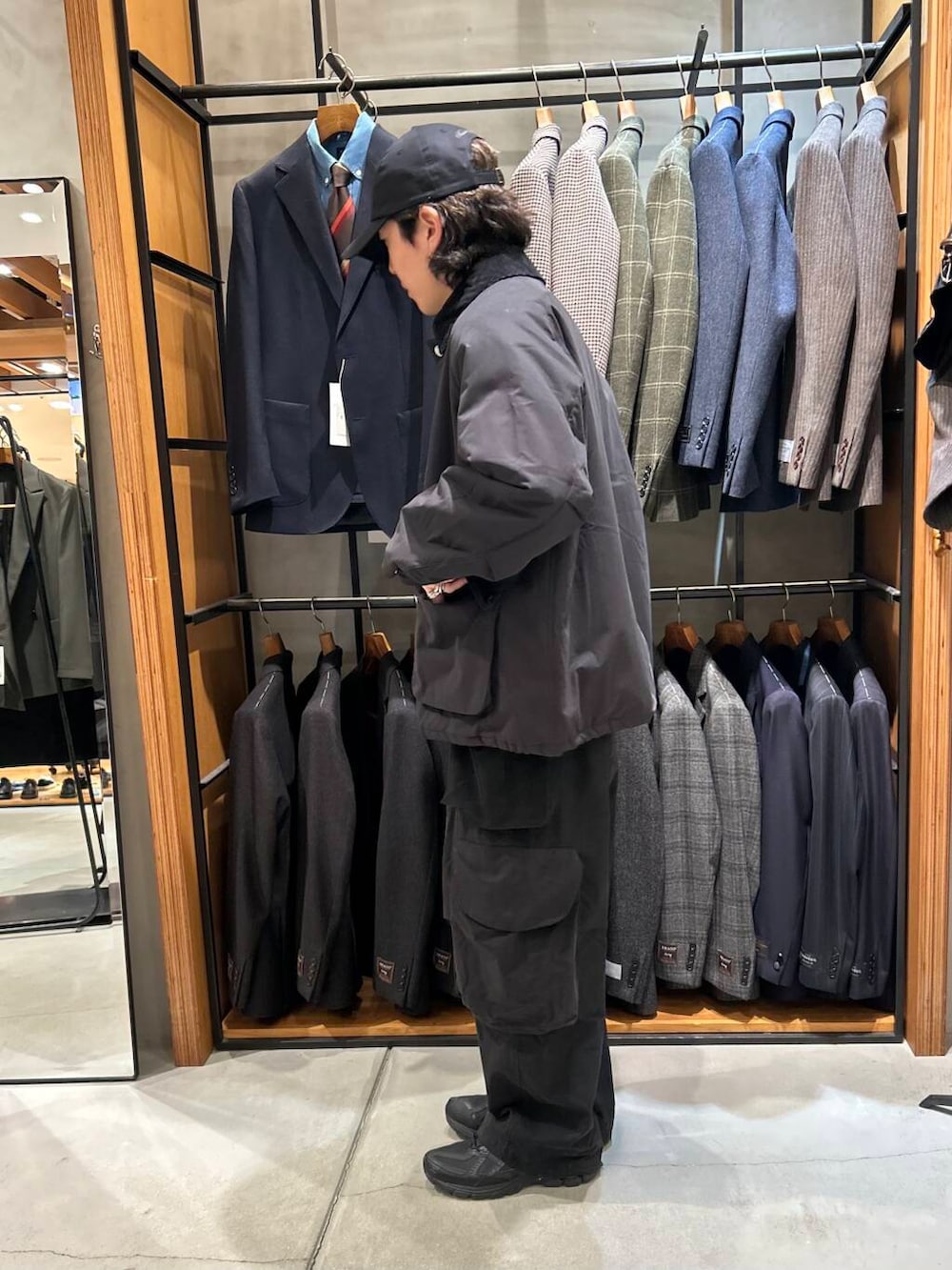 グレー系のニット/セーター、ブラック系のダウンジャケット/コート、ブラック系のキャップを着用したメンズの冬コーディネートの3枚目の写真