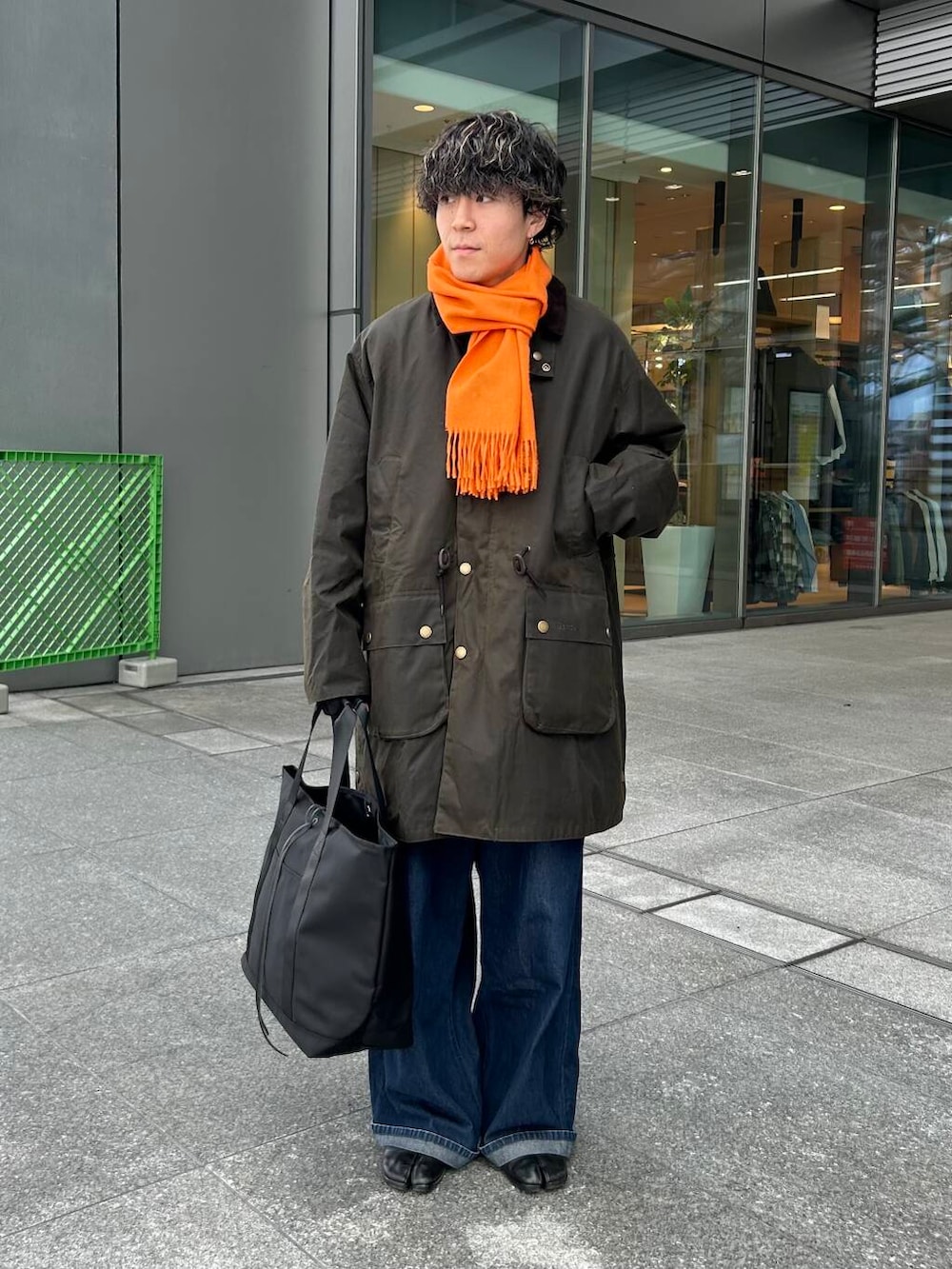 ブラック系のトートバッグ、グリーン系のステンカラーコート、ブラック系の手袋を着用したメンズの秋コーディネートの2枚目の写真