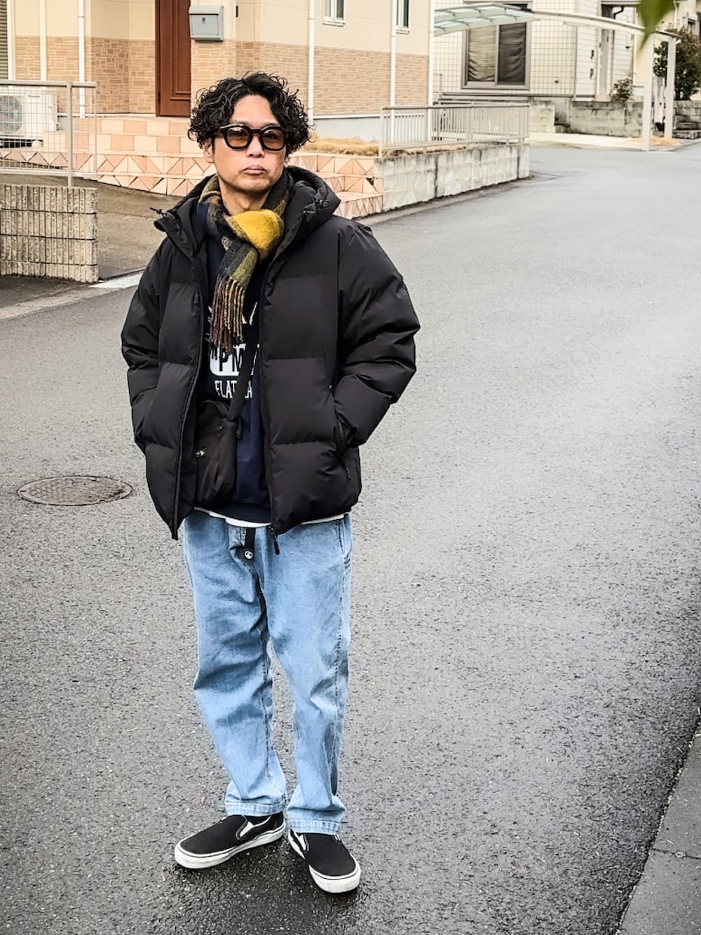 ブラック系のダウンジャケット/コート、ブルー系のチノパンツ、ブラック系のスリッポンを着用したメンズの冬コーディネートの2枚目の写真