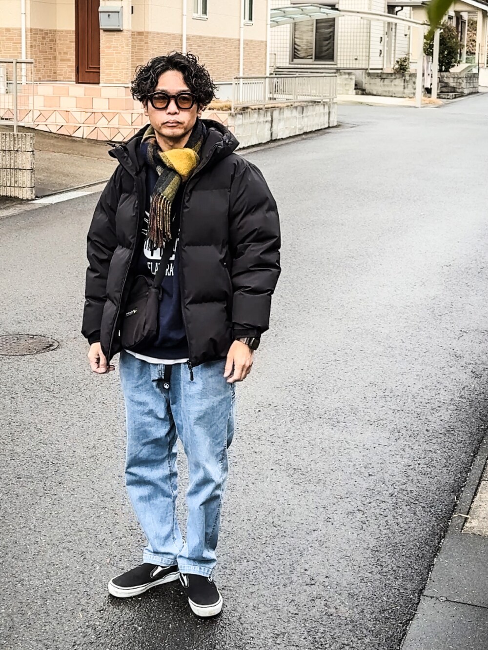 ブラック系のダウンジャケット/コート、ブルー系のチノパンツ、ブラック系のスリッポンを着用したメンズの冬コーディネートの3枚目の写真