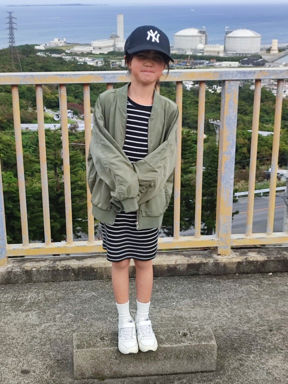 グリーン系のMA-1、ブラック系のワンピース、ホワイト系のスニーカーを着用したキッズの冬コーディネートの2枚目の写真