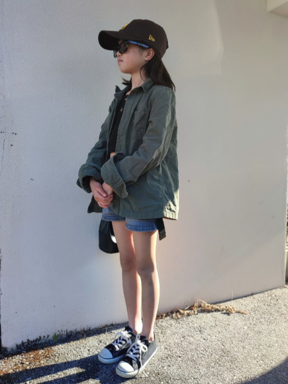 グリーン系のミリタリージャケット、ブルー系のデニムパンツ、ブラック系のスニーカーを着用したキッズの春コーディネートの3枚目の写真