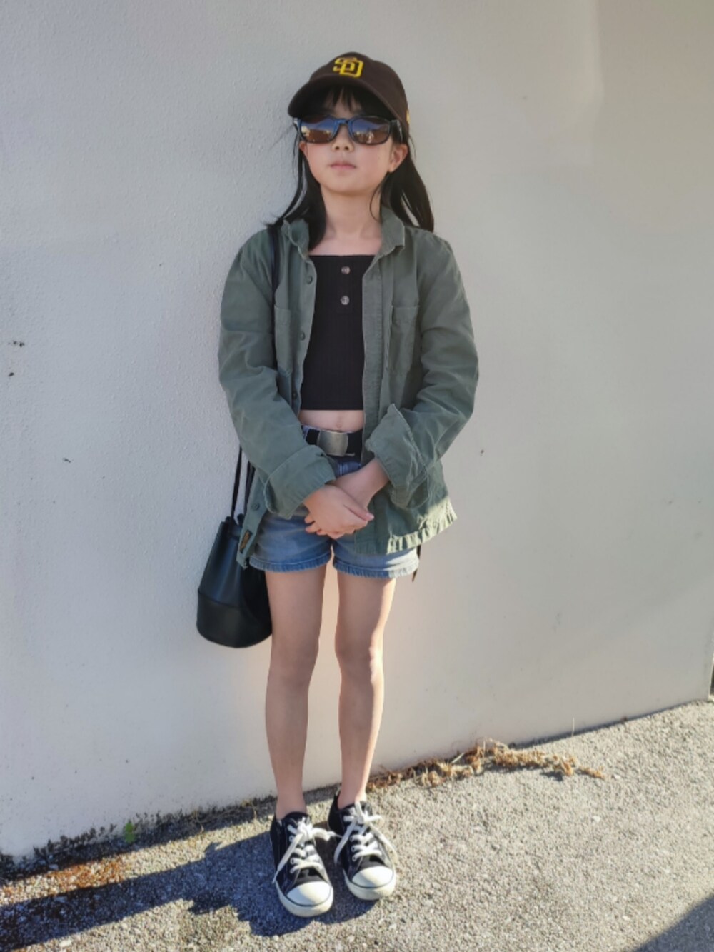 グリーン系のミリタリージャケット、ブルー系のデニムパンツ、ブラック系のスニーカーを着用したキッズの春コーディネートの2枚目の写真