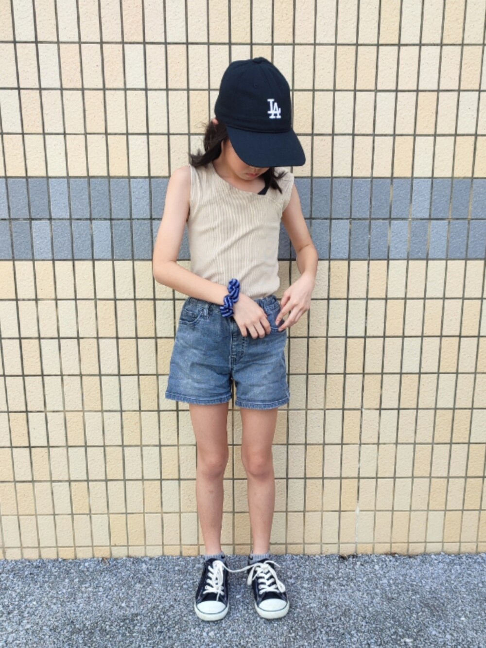 ベージュ系のタンクトップ、グレー系のデニムパンツ、ブラック系のスニーカーを着用したキッズの夏コーディネートの3枚目の写真