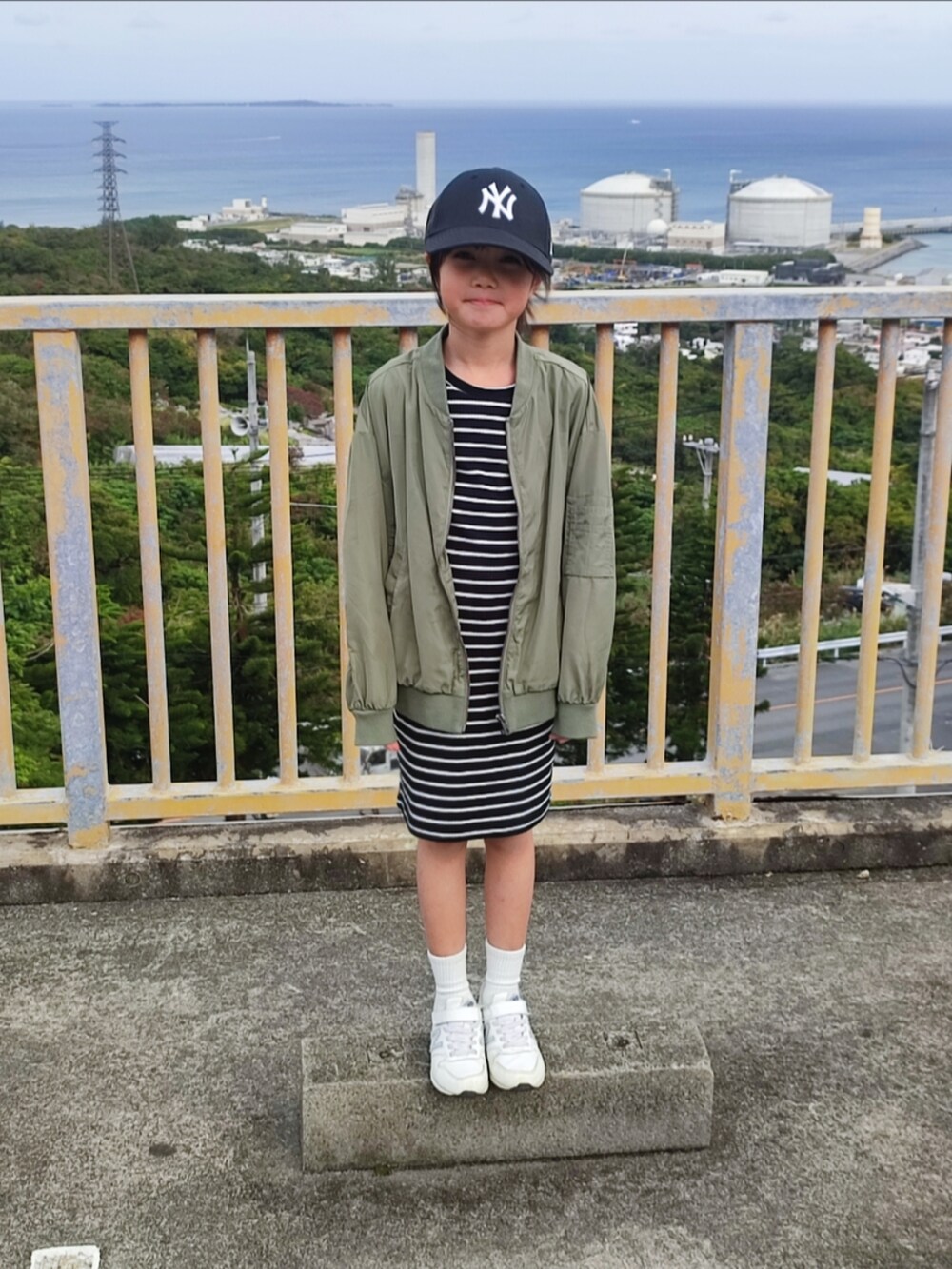 グリーン系のMA-1、ブラック系のワンピース、ホワイト系のスニーカーを着用したキッズの冬コーディネートの3枚目の写真