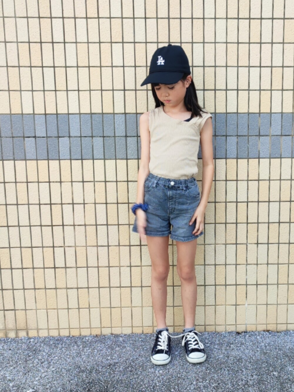 ベージュ系のタンクトップ、グレー系のデニムパンツ、ブラック系のスニーカーを着用したキッズの夏コーディネートの4枚目の写真