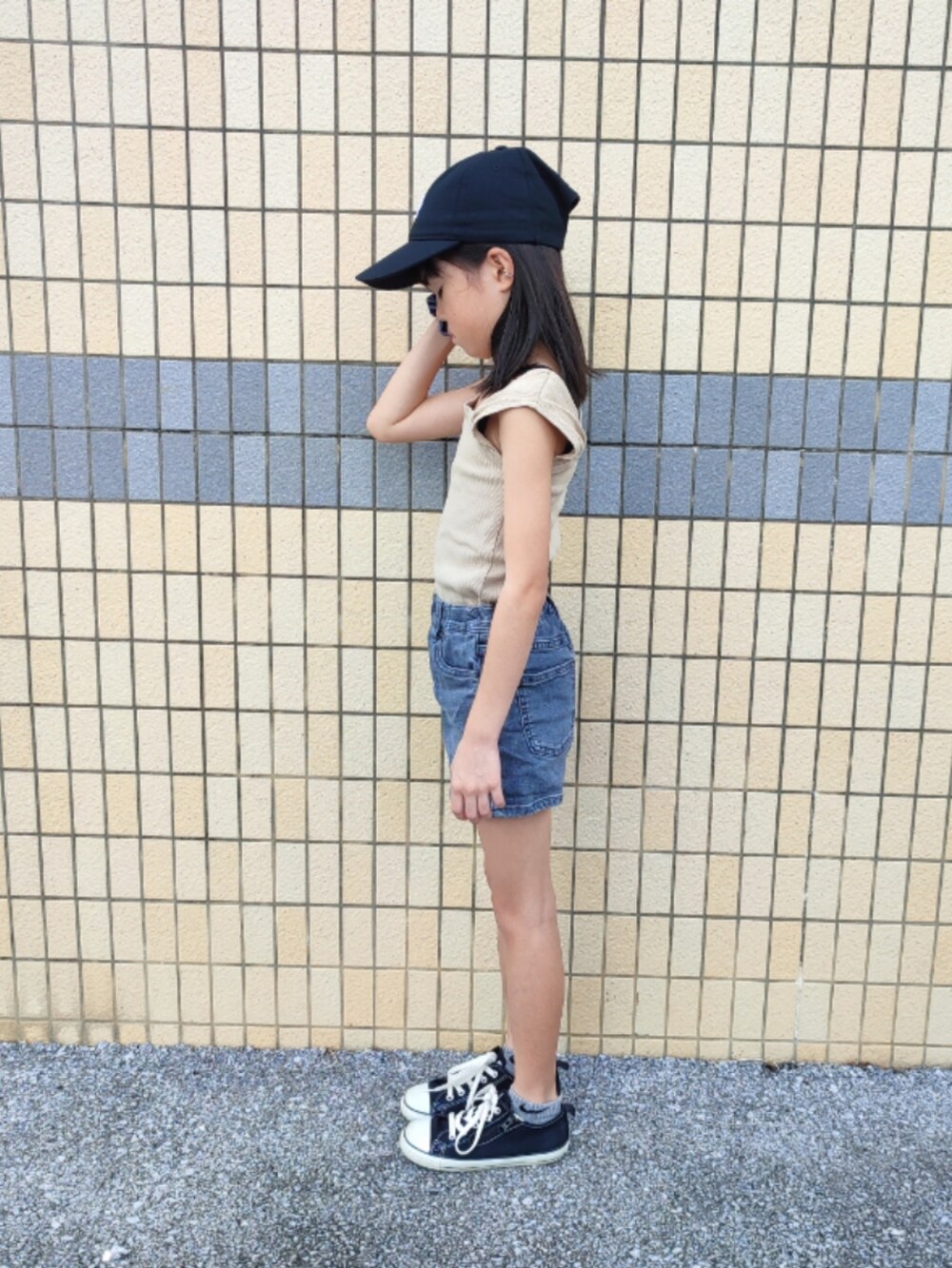 ベージュ系のタンクトップ、グレー系のデニムパンツ、ブラック系のスニーカーを着用したキッズの夏コーディネートの2枚目の写真