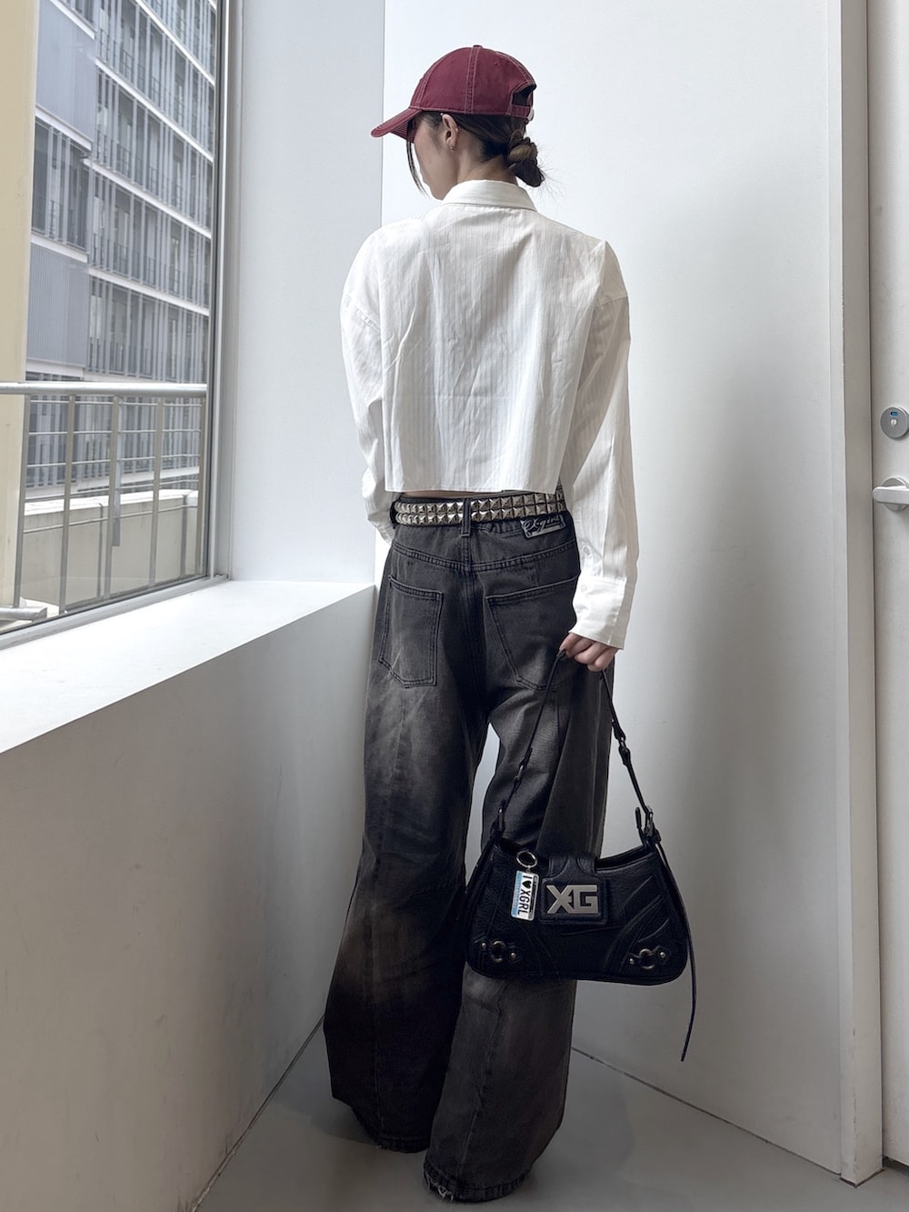 ブラック系のデニムパンツ、ホワイト系のシャツ/ブラウス、ブラック系のショルダーバッグを着用したレディースの春コーディネートの3枚目の写真