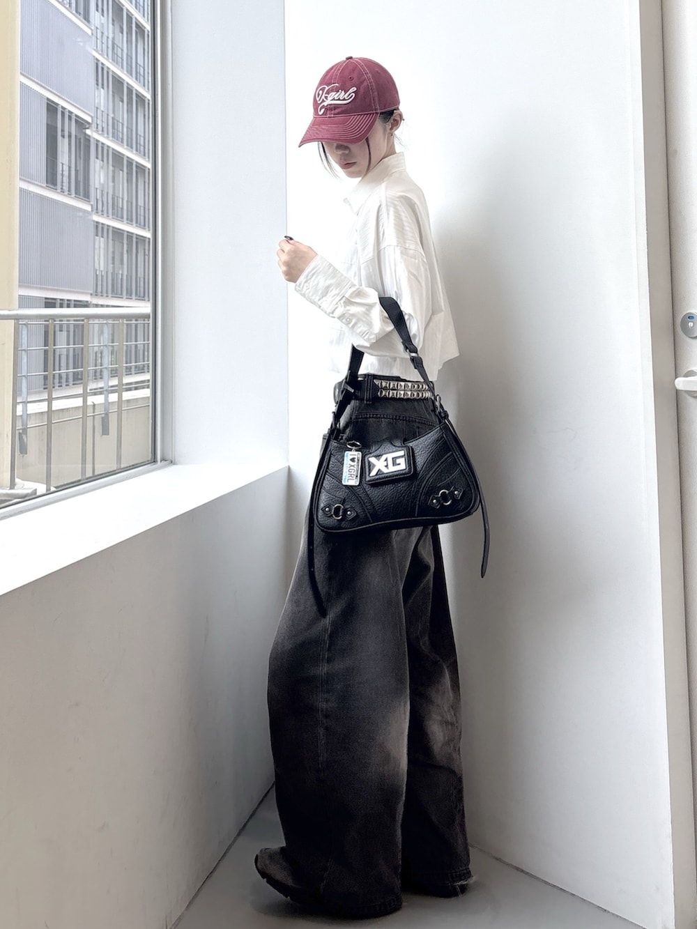 ブラック系のデニムパンツ、ホワイト系のシャツ/ブラウス、ブラック系のショルダーバッグを着用したレディースの春コーディネートの2枚目の写真