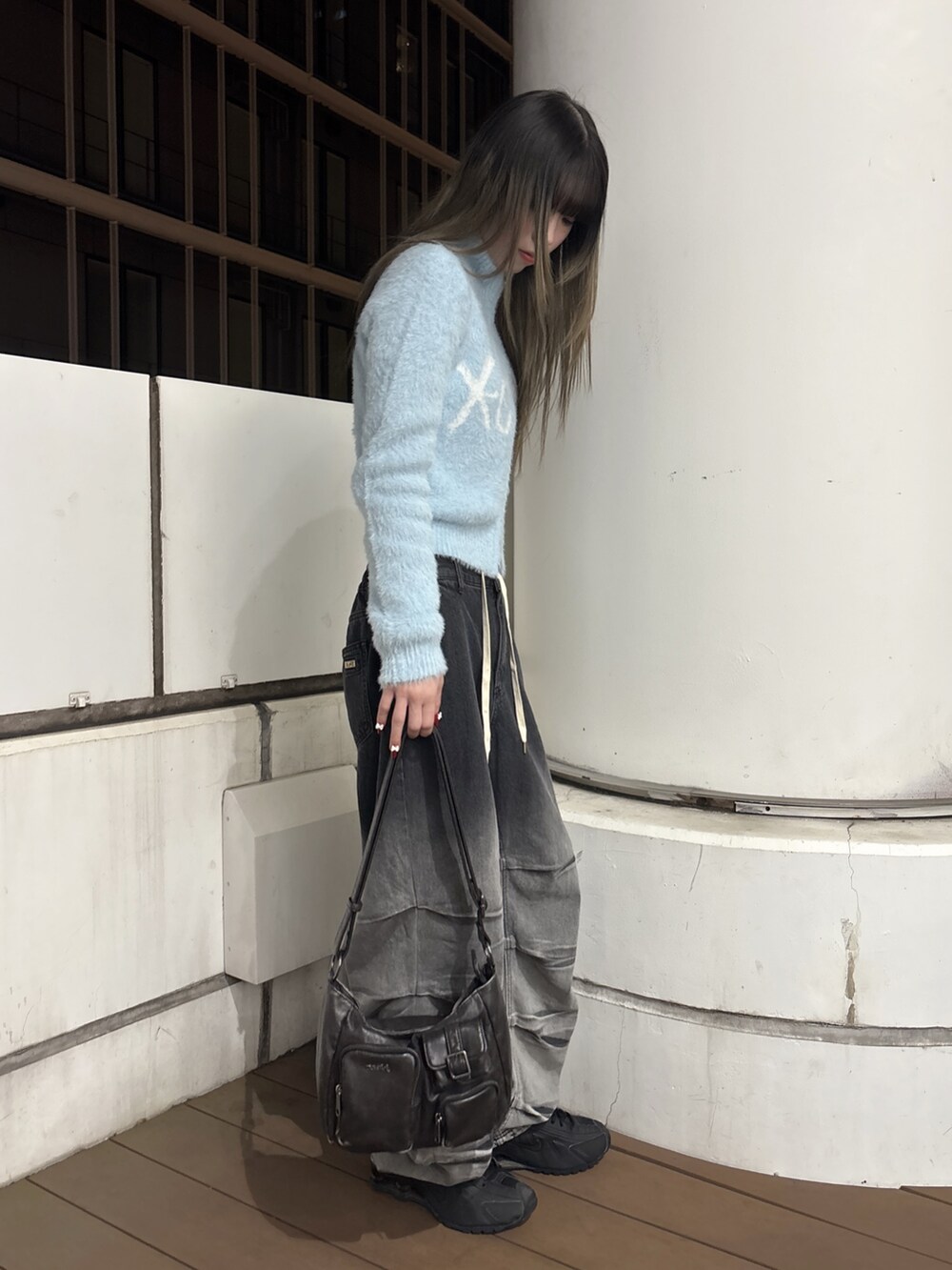 ブラック系のデニムパンツ、ブラック系のショルダーバッグ、ブルー系のニット/セーターを着用したレディースの秋コーディネートの2枚目の写真