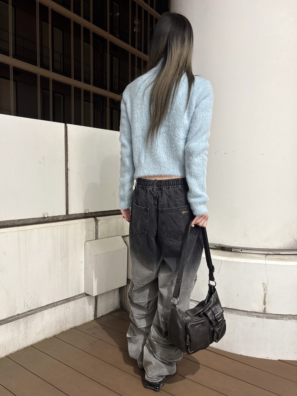 ブラック系のデニムパンツ、ブラック系のショルダーバッグ、ブルー系のニット/セーターを着用したレディースの秋コーディネートの3枚目の写真