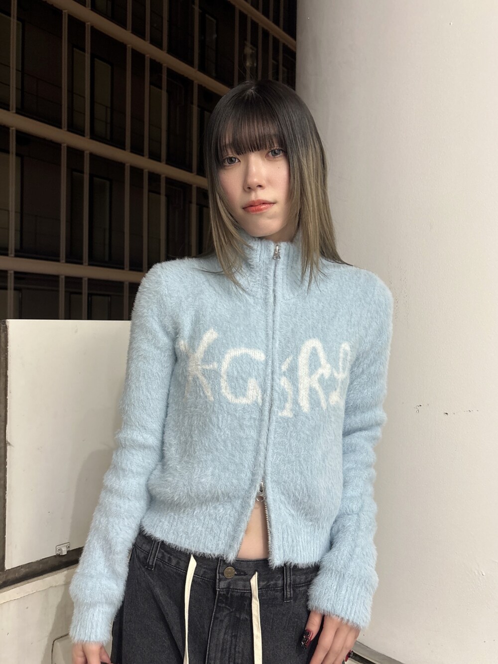 ブラック系のデニムパンツ、ブラック系のショルダーバッグ、ブルー系のニット/セーターを着用したレディースの秋コーディネートの4枚目の写真