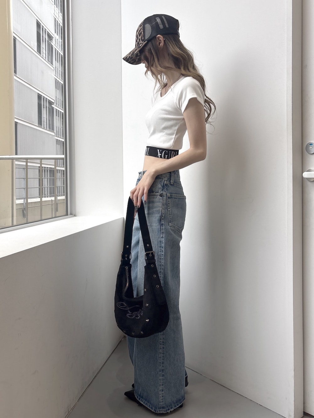ブルー系のデニムパンツ、ブラック系のショルダーバッグ、ホワイト系のTシャツ/カットソーを着用したレディースの春コーディネートの2枚目の写真