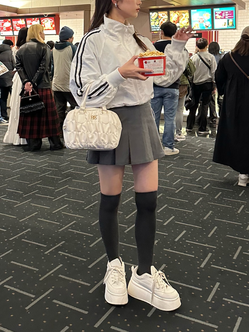 ホワイト系のナイロンジャケット、グレー系のスカートを着用したレディースの春コーディネートの2枚目の写真