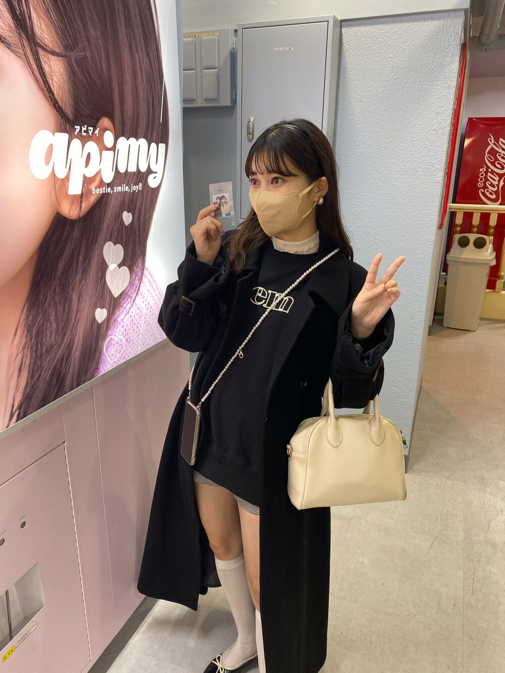 ブラック系のステンカラーコート、ブラック系のスウェットを着用したレディースの冬コーディネートの3枚目の写真