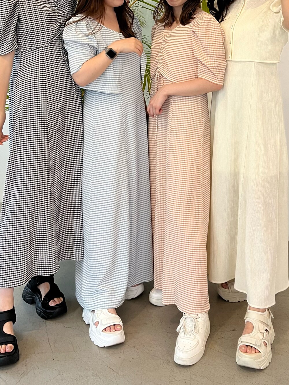 オレンジ系のワンピース、ホワイト系のサンダル、ホワイト系のキャップを着用したレディースの夏コーディネートの2枚目の写真