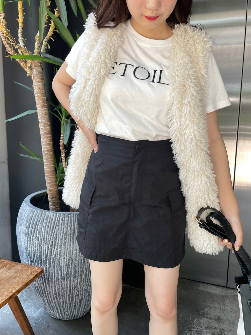 ブラック系のスカート、ホワイト系のベスト、ホワイト系のTシャツ/カットソーを着用したレディースの夏コーディネートの3枚目の写真