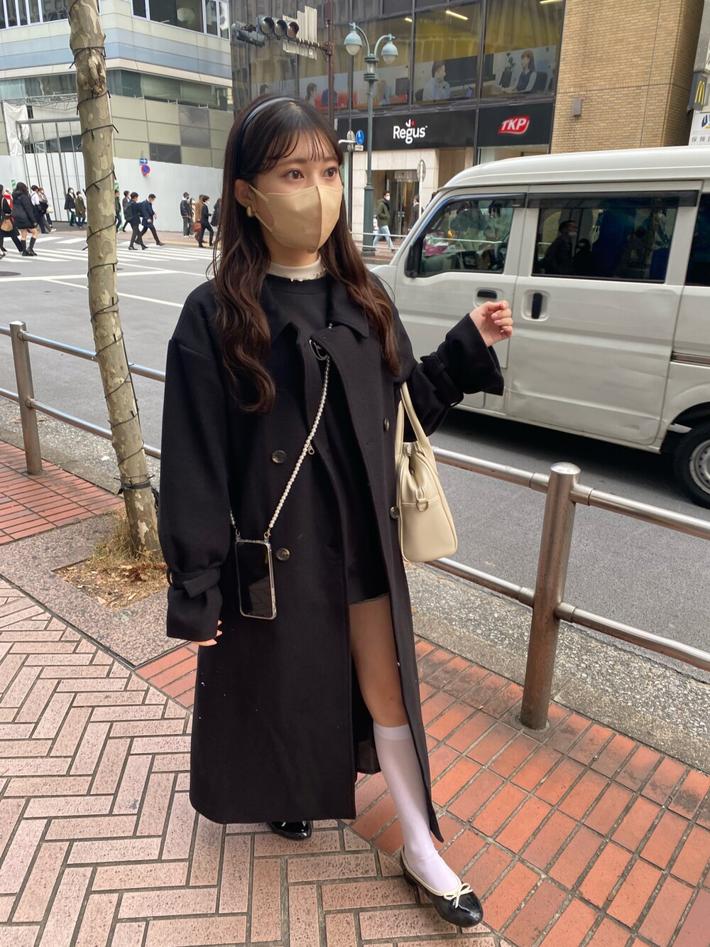 ブラック系のステンカラーコート、ブラック系のスウェットを着用したレディースの冬コーディネートの2枚目の写真