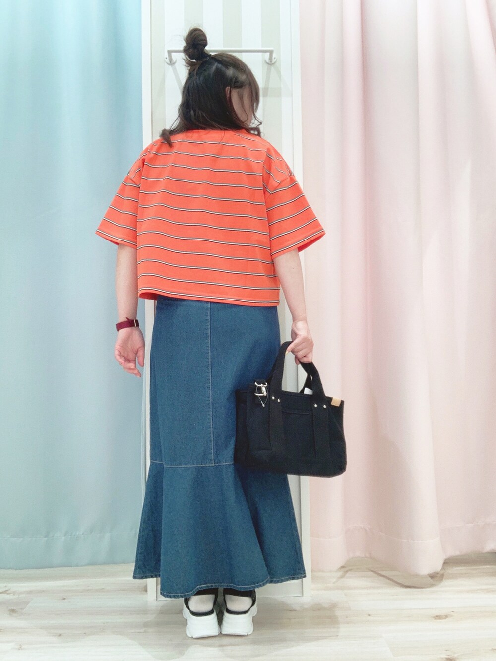 オレンジ系のTシャツ/カットソー、ブルー系のスカート、ブラック系のトートバッグを着用したレディースの夏コーディネートの3枚目の写真