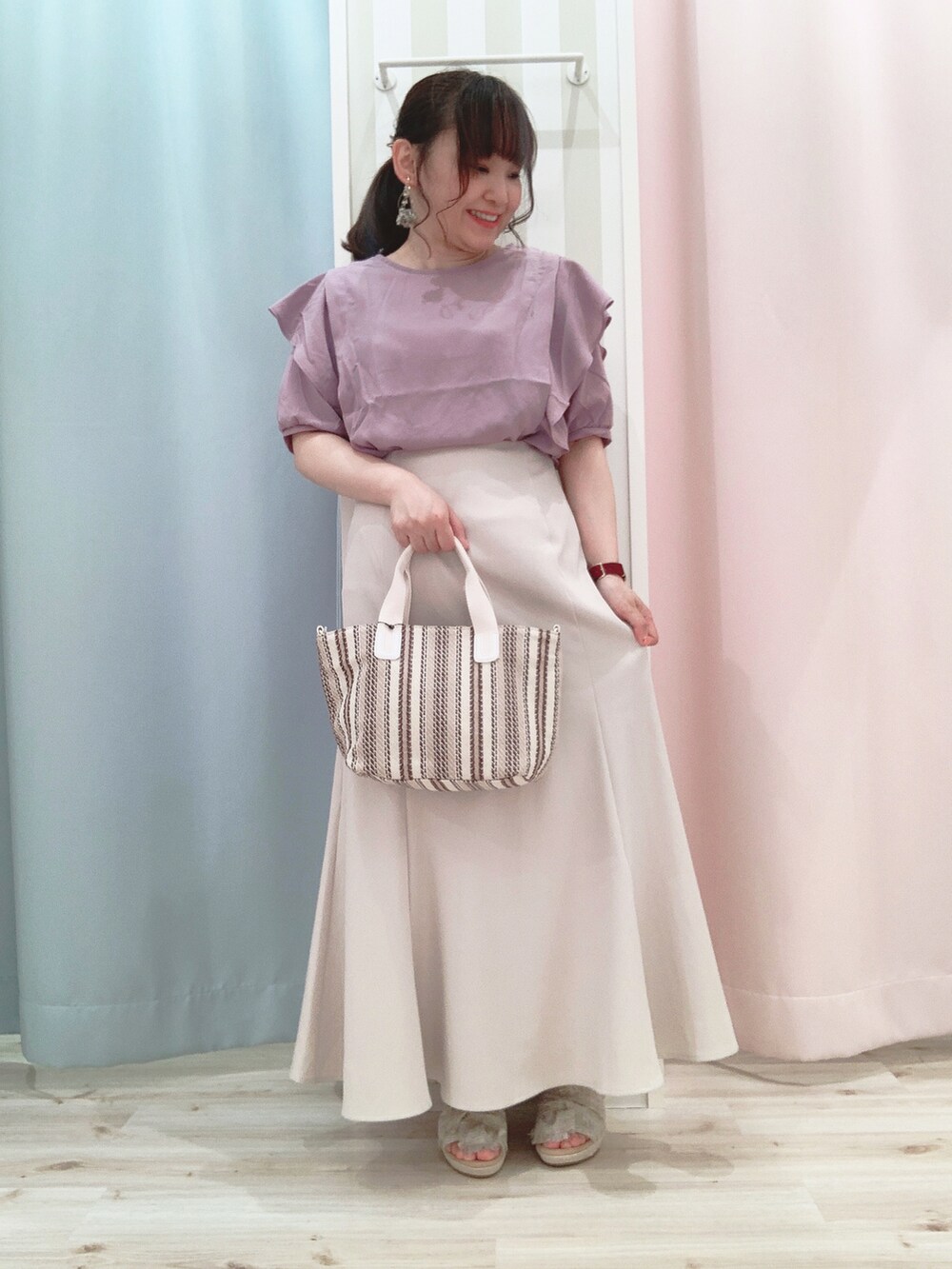 パープル系のシャツ/ブラウス、ベージュ系のスカート、ベージュ系のトートバッグを着用したレディースの夏コーディネートの2枚目の写真