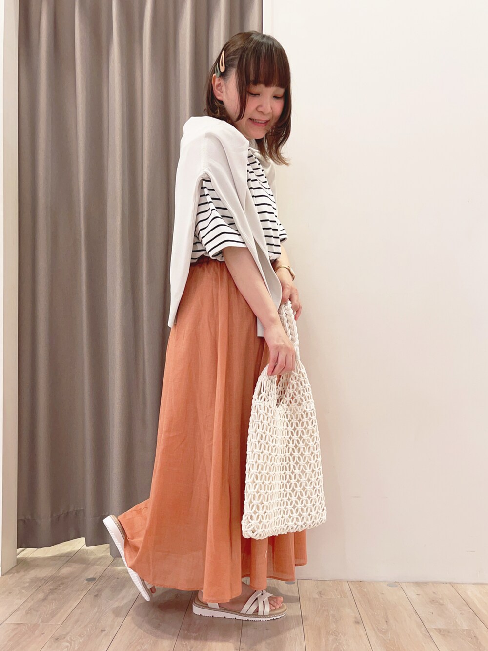 ホワイト系のTシャツ/カットソー、グレー系のカーディガン/ボレロ、オレンジ系のスカートを着用したレディースの春コーディネートの2枚目の写真