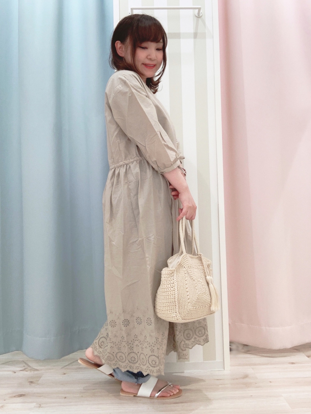 ベージュ系のワンピース、ブルー系のデニムパンツ、ホワイト系のサンダルを着用したレディースの春コーディネートの2枚目の写真