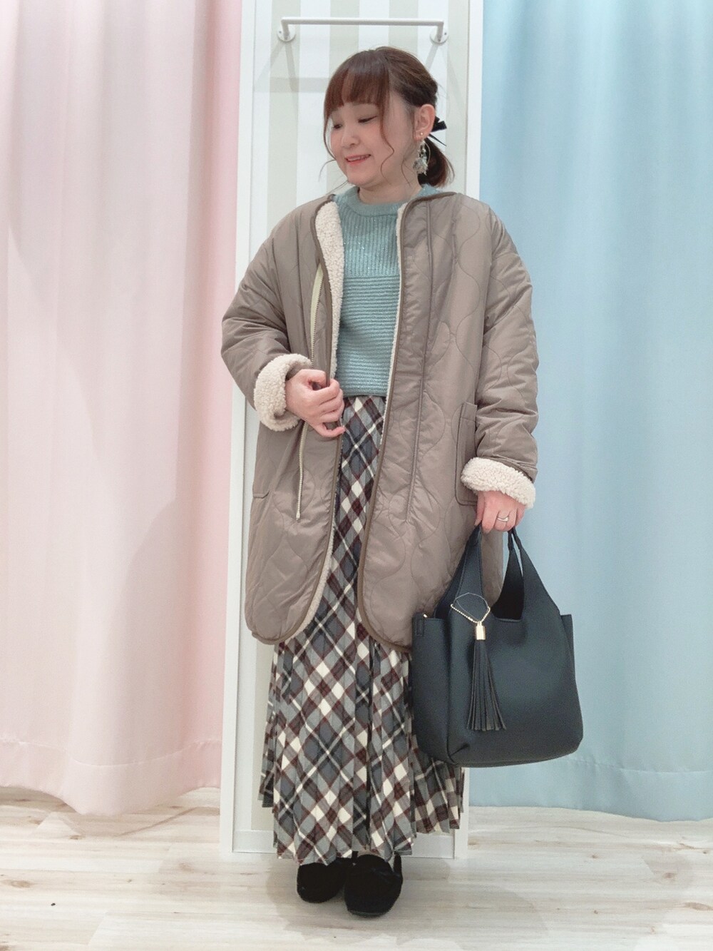 ベージュ系のその他アウター、グリーン系のニット/セーター、レッド系のスカートを着用したレディースの冬コーディネートの2枚目の写真