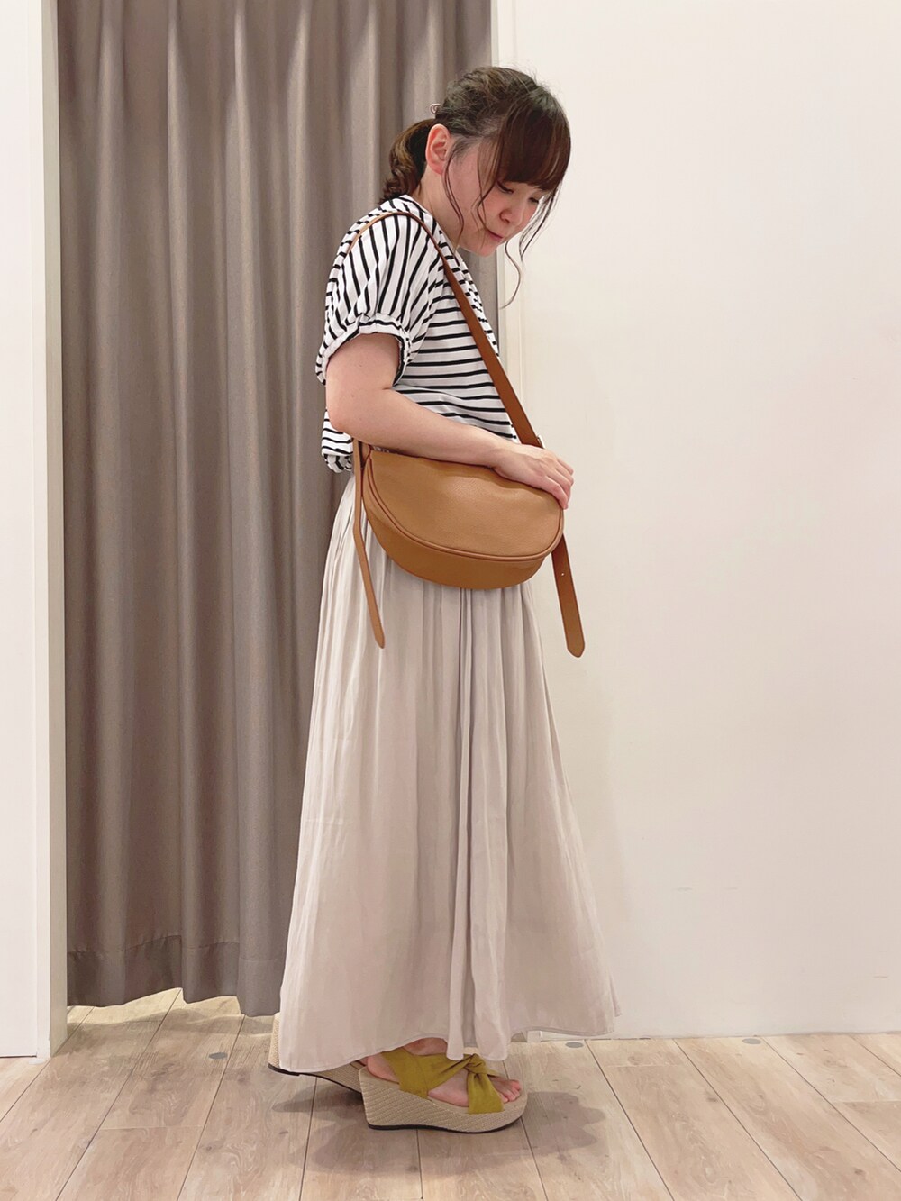 グレー系のスカート、イエロー系のショルダーバッグ、イエロー系のサンダルを着用したレディースの夏コーディネートの2枚目の写真