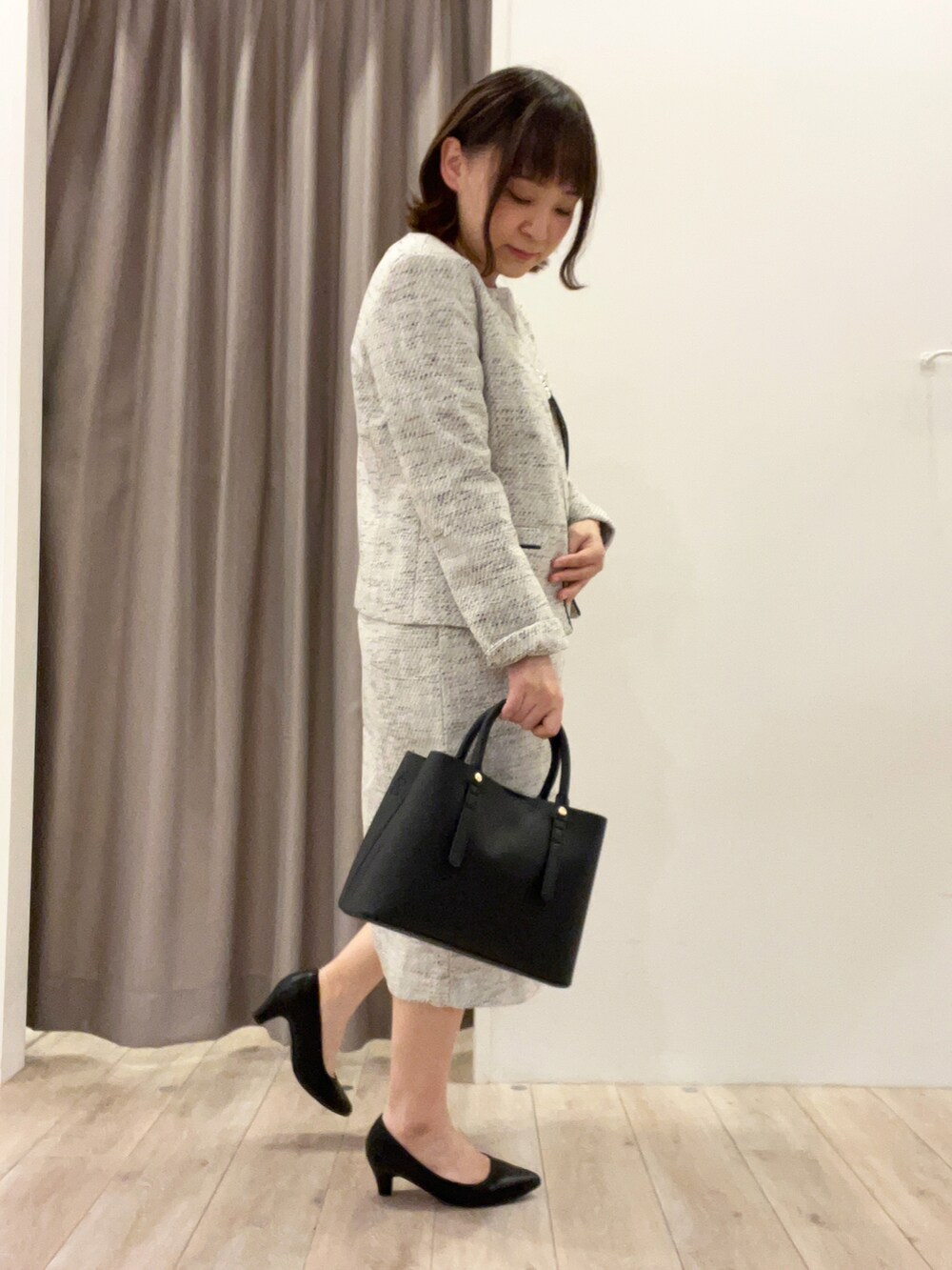 グレー系のワンピース、グレー系のノーカラージャケット、ブラック系のトートバッグを着用したレディースの冬コーディネートの2枚目の写真